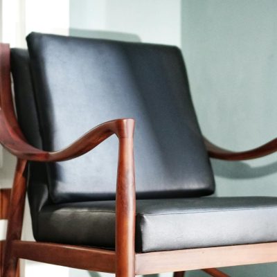 Close-up of a wooden chair with leather cushions in a modern interior setting.